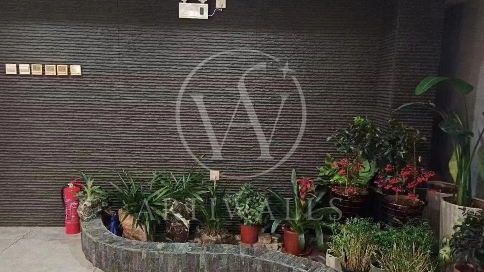 Dinding taman bertekstur hitam dengan tanaman di bagian depan